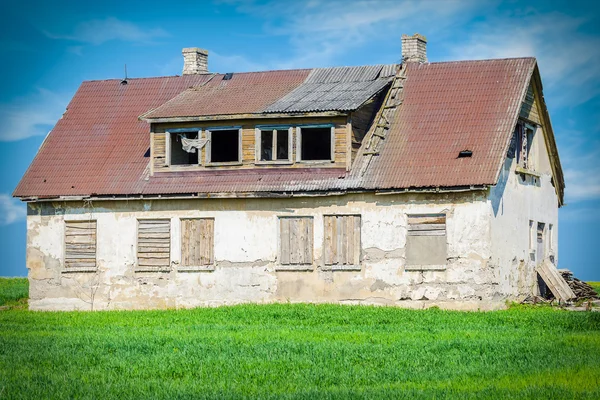 Oude verlaten beschadigd huis op grasveld — Stockfoto