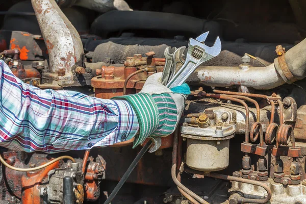 Tangan manusia dengan kunci pas disesuaikan dekat mesin diesel tua — Stok Foto