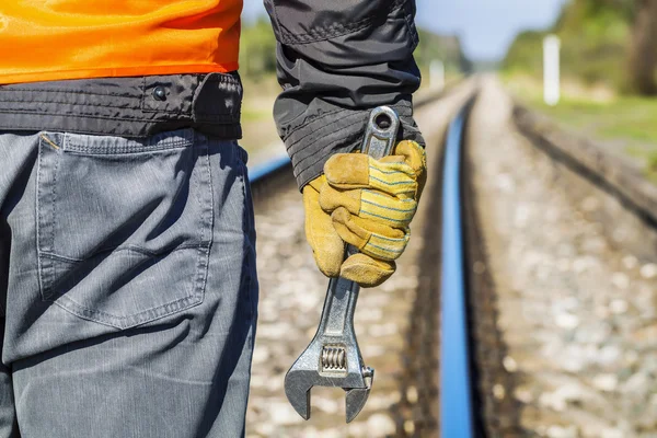 Railroad worker with adjustable wrench on railway in spring — Stock Photo, Image