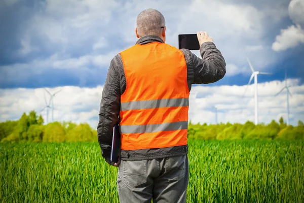 Farmer take pictures on smart phone near the green cereal field — Stock Photo, Image