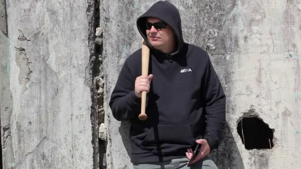 Man with a baseball bat watching near wall — Stock Video