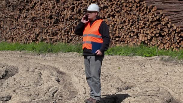 Lumberjack marche et parle sur le téléphone intelligent près du journal de pile — Video