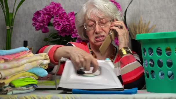 Donna anziana stiratura e parlare su smart phone — Video Stock