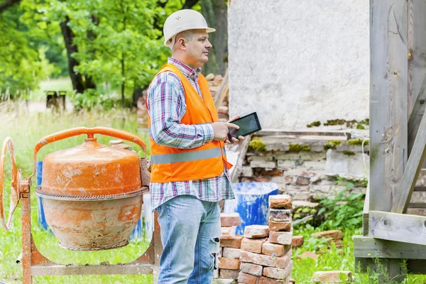 Pracownik budowlany za pomocą tabletu Pc w pobliżu betoniarki — Zdjęcie stockowe