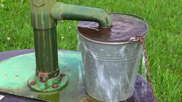 Água que flui sobre as bordas do balde perto da bomba de água — Vídeo de Stock
