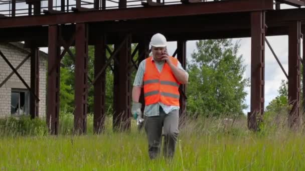 Arbetare med skiftnyckel promenader och talar i mobiltelefon — Stockvideo