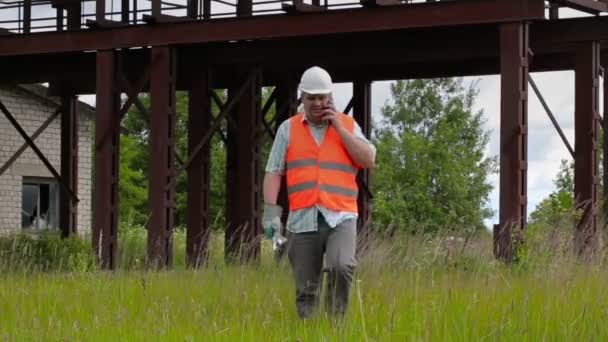 Trabajador con llave ajustable caminando y hablando por teléfono celular — Vídeos de Stock