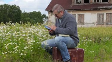Adam bavul üzerinde oturan ve tablet Pc kullanma 