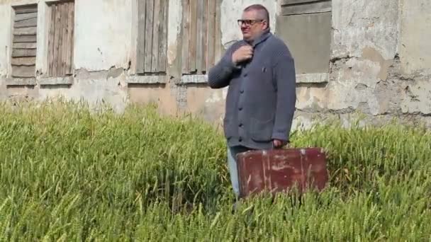 Hombre con maleta bostezando cerca del edificio abandonado — Vídeos de Stock