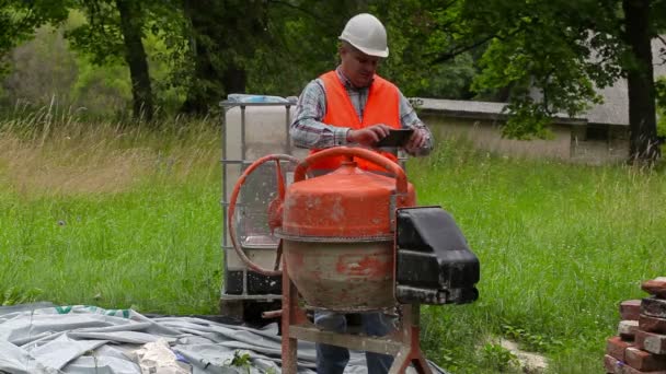 İnşaat işçisi Tablet Pc beton mikser yakınındaki fotoğraf çekmek — Stok video