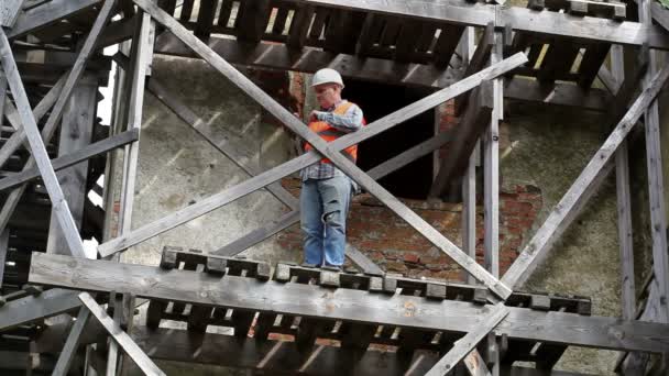 Trabajador de la construcción de pie sobre andamios de madera y utilizando tableta PC — Vídeo de stock