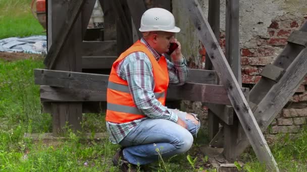 Bouw werknemer controle houten steigers en praten over slimme telefoon — Stockvideo