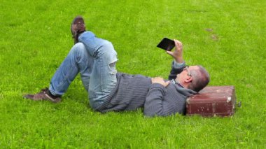Adam akıllı telefon üzerinde çim ve almak resimlerdeki uyku çanta 