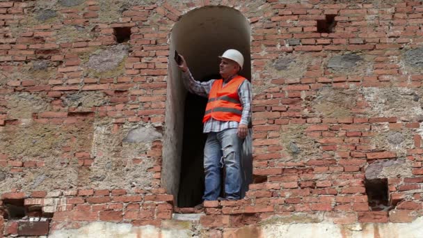 Trabajador de la construcción tomar fotos en el teléfono inteligente cerca de la pared vieja — Vídeo de stock