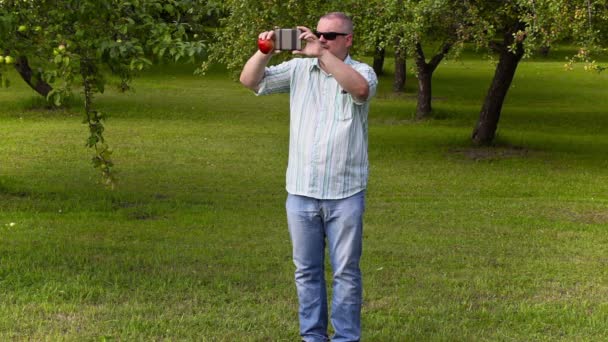 Giardiniere scattare foto e camminare nel frutteto di mele — Video Stock