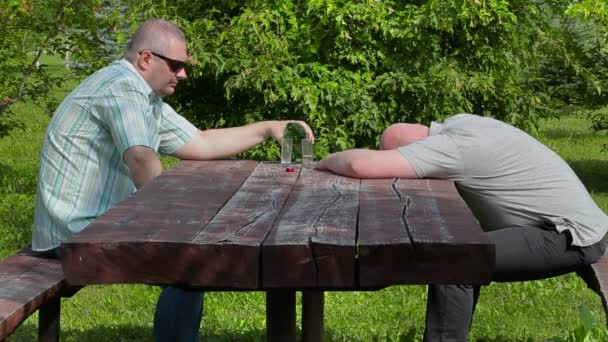 Muž nalil a vypít sklenku alkoholu další opilý muž spí — Stock video