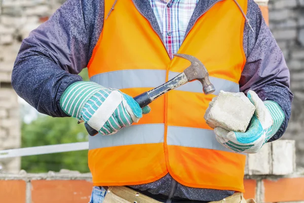 Travailleur de la construction divise la brique avec marteau — Photo