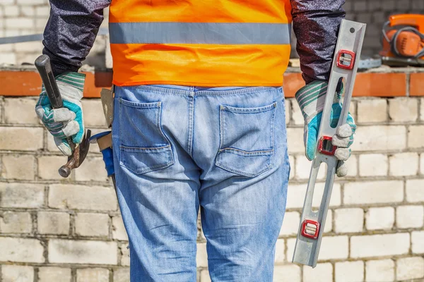 Builder with spirit level and hammer — Stock Photo, Image