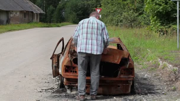 Stressgeplagter Mann sorgt sich um ausgebranntes Autowrack am Straßenrand — Stockvideo