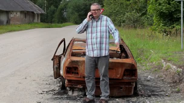 Homme stressant parlant sur le téléphone intelligent et coup de pied épave de voiture — Video