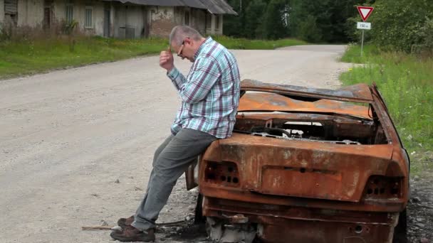 Стрессовый человек на сгоревшей автокатастрофе на обочине дороги — стоковое видео