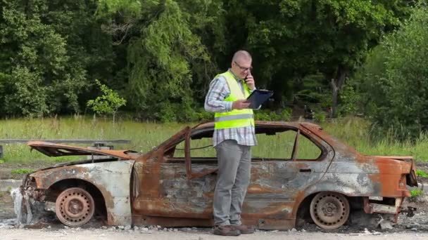 Inspektor, czytania i rozmowy na inteligentnego telefonu w pobliżu wraku samochodu na drodze — Wideo stockowe