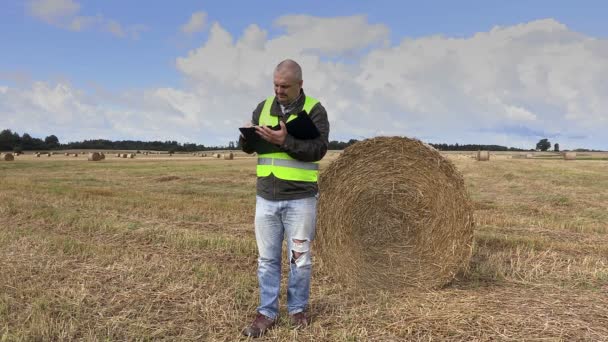 Zemědělec na poli nedaleko balíky slámy — Stock video