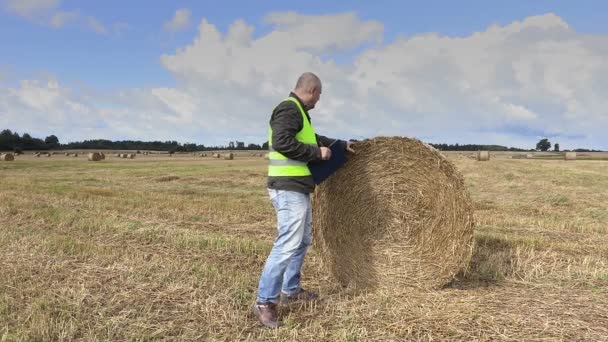 Фермер на поле возле соломенного тюка — стоковое видео