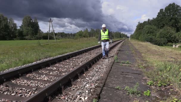 Railroad worker with cell phone and adjustable wrench walking near railway in slow motion — Stock Video