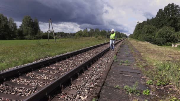 Працівник залізниці з регульованим ключем, що йде поблизу залізниці — стокове відео