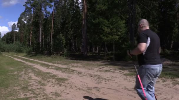 Caminante con bastones caminando por la carretera forestal en 4K — Vídeos de Stock
