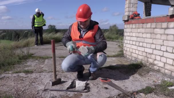 Trabajador de la construcción divide ladrillo con martillo — Vídeo de stock