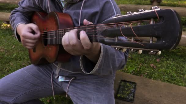 Άνθρωπος παίζοντας κιθάρα σε παγκάκι — Αρχείο Βίντεο