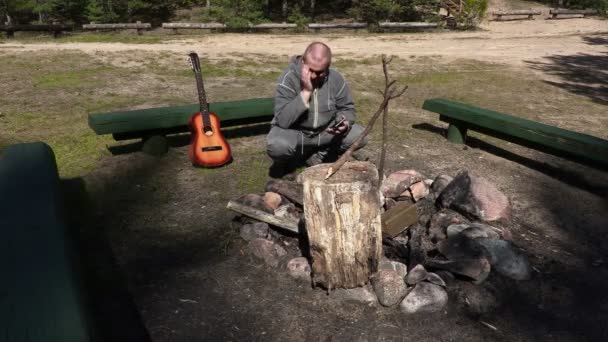 Hiker with tablet laughing at the fire site — Stock Video