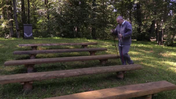 Unavený turista s vycházkové hole na lavičce v parku — Stock video