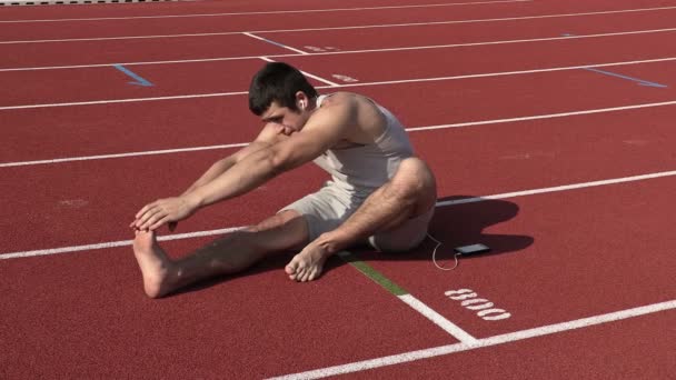 Joven atleta estirándose en el estadio — Vídeo de stock