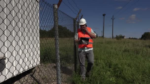 Инженер читает и разговаривает на смартфоне — стоковое видео