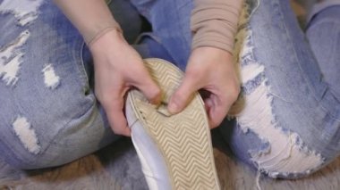 Kadın eski beyaz ayakkabılarını inceliyor.