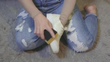 Beyaz ayakkabılarını temizleyen kadın.