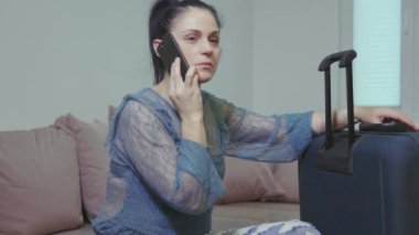  Büyük bagajların yanında akıllı telefondan konuşan kadın.