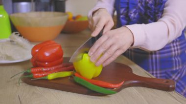 Mutfakta biber kesen bir kadın var.