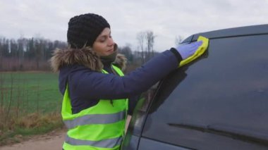 Arabasını temizleyen ve baş parmağını gösteren mutlu bir kadın.