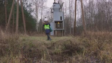 Kadın elektrik mühendisi trafo ile düşük voltaj hattını kontrol ediyor.
