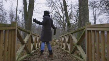 Parktaki tahta köprüde mutlu sarhoş bir kadın.