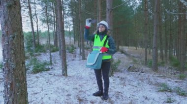 Kadın orman bilimcisi, kozalaklı alanda fotoğraf çekiyor.