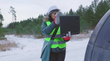 Kış ormanlarında dizüstü bilgisayarı olan bir kadın orman bilimcisi.