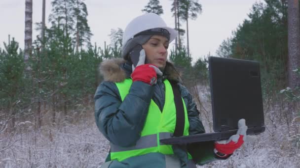 冬にスマートフォンやノートパソコンを使う女性森林科学者 — ストック動画