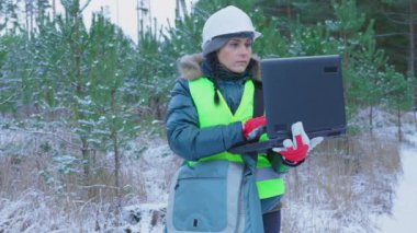 PC kullanan ve genç çam standlarını inceleyen bir kadın.