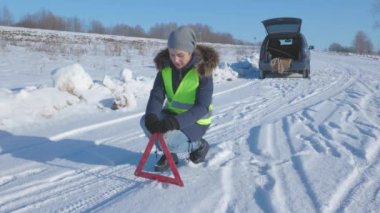 Uyarı üçgeniyle arabanın yanında duran kadın.