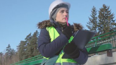 Kadın mühendis kışın köprüye yakın düşünüyor.